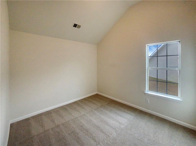 empty room with carpet, visible vents, vaulted ceiling, and baseboards