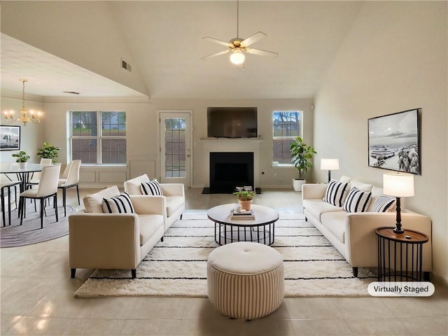 tiled living room with ceiling fan with notable chandelier, high vaulted ceiling, a fireplace, and visible vents