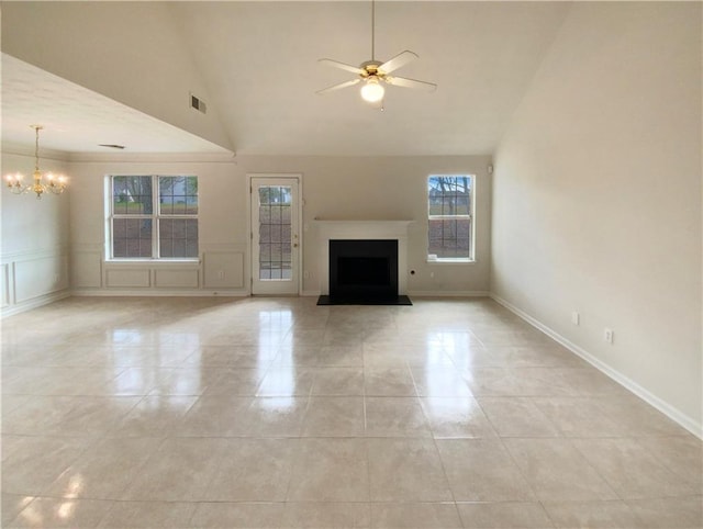 unfurnished living room with light tile patterned flooring, a decorative wall, ceiling fan with notable chandelier, a fireplace with flush hearth, and visible vents