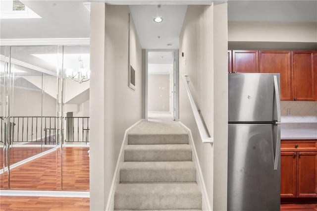 staircase featuring hardwood / wood-style flooring and a notable chandelier