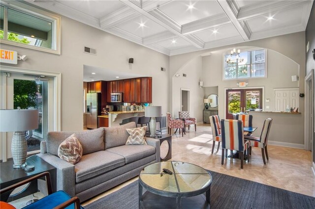 tiled living room featuring beamed ceiling, french doors, a high ceiling, and an inviting chandelier