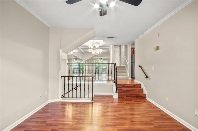 stairs with hardwood / wood-style floors, ceiling fan with notable chandelier, and ornamental molding