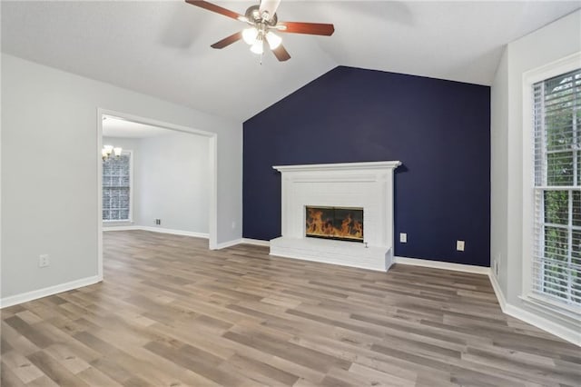 unfurnished living room featuring lofted ceiling, a fireplace, and light hardwood / wood-style flooring