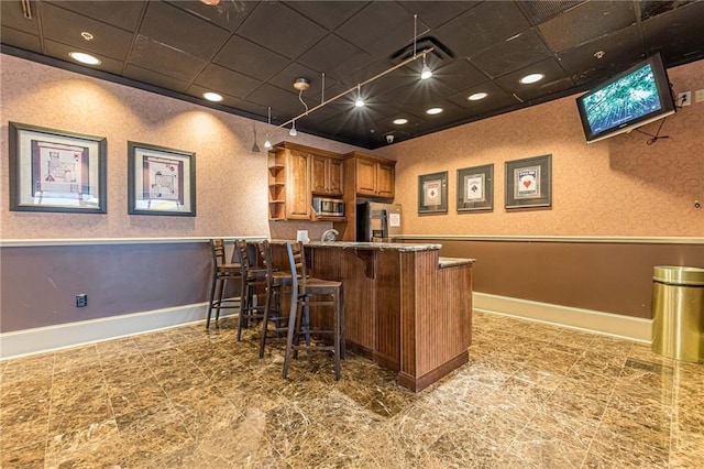 bar with appliances with stainless steel finishes and a drop ceiling