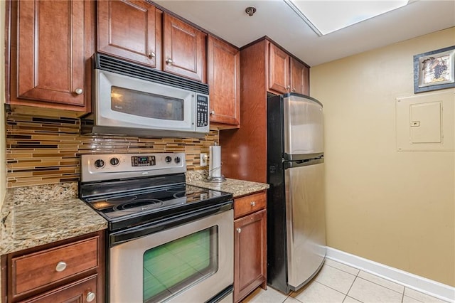 kitchen with light stone counters, backsplash, electric panel, light tile patterned flooring, and appliances with stainless steel finishes