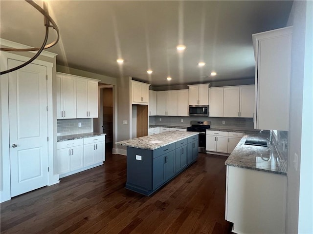 kitchen with white cabinets, appliances with stainless steel finishes, dark hardwood / wood-style flooring, and a kitchen island