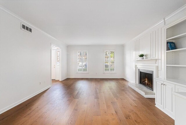 6 Stratford Hall Pl NE, Atlanta, GA 30342 - unfurnished living room featuring light wood-style flooring, a large fireplace, baseboards, built in shelves, and crown molding