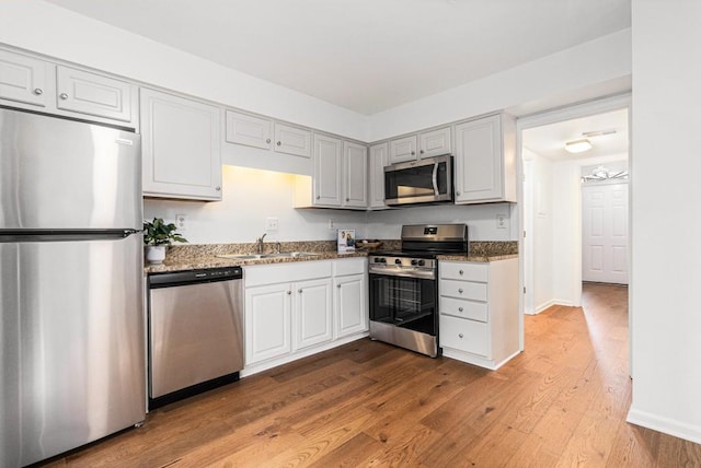 6 Stratford Hall Pl NE, Atlanta, GA 30342 - kitchen with appliances with stainless steel finishes, light wood-type flooring, dark stone countertops, and a sink