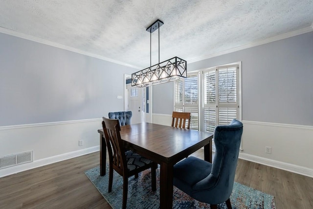 dining room with crown molding, visible vents, dark wood finished floors, and a textured ceiling