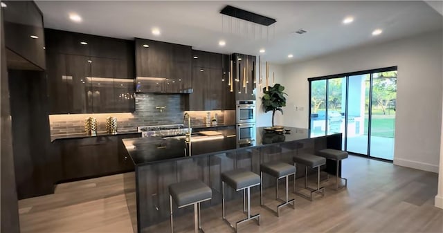 6711 Bishop Rd, Fairburn, GA 30213 - kitchen with modern cabinets, dark countertops, light wood-type flooring, a breakfast bar, and tasteful backsplash