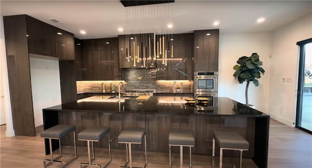 6711 Bishop Rd, Fairburn, GA 30213 - kitchen featuring modern cabinets, dark countertops, light wood finished floors, backsplash, and recessed lighting
