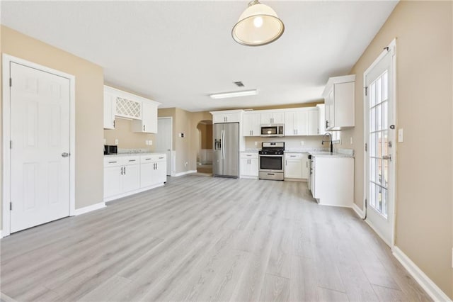 kitchen featuring stainless steel appliances, light wood-type flooring, light countertops, and white cabinetry