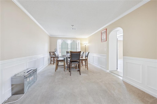 dining room with carpet, arched walkways, a textured ceiling, and ornamental molding