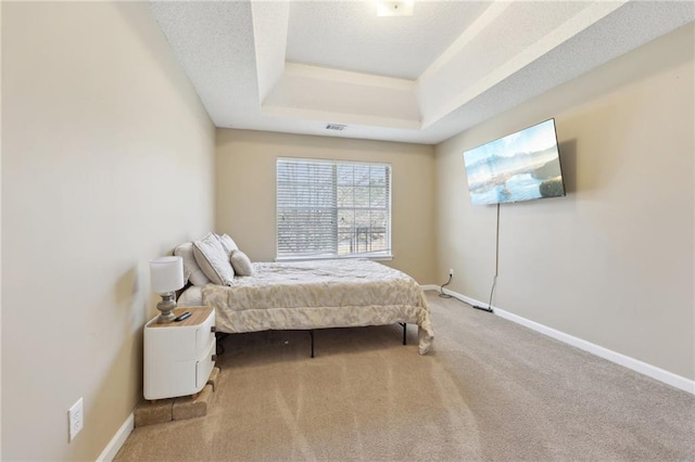 carpeted bedroom featuring baseboards, visible vents, a raised ceiling, and a textured ceiling