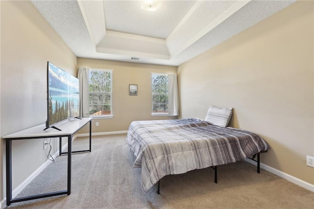 bedroom featuring a tray ceiling, carpet flooring, a textured ceiling, and baseboards