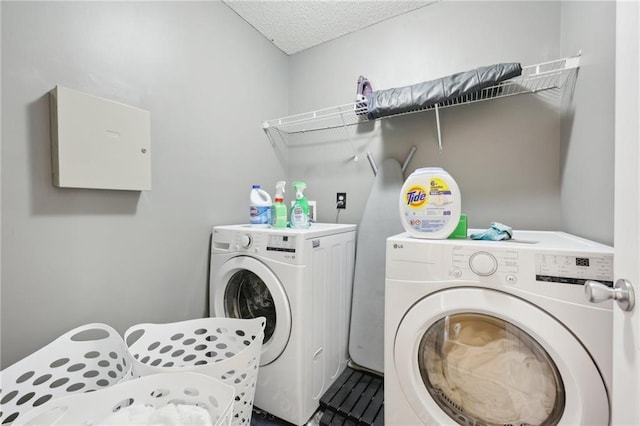 washroom with laundry area, a textured ceiling, and separate washer and dryer