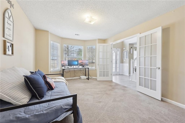 living area with french doors, visible vents, carpet flooring, a textured ceiling, and baseboards