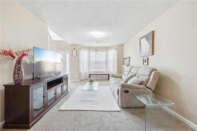 living area with a textured ceiling, carpet flooring, and baseboards