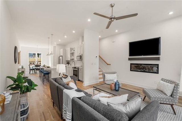 living room featuring ceiling fan and light hardwood / wood-style floors