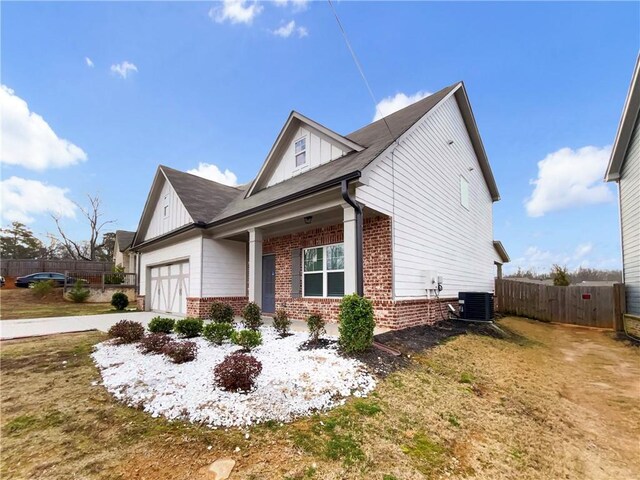 view of side of property featuring a garage, brick siding, board and batten siding, and fence