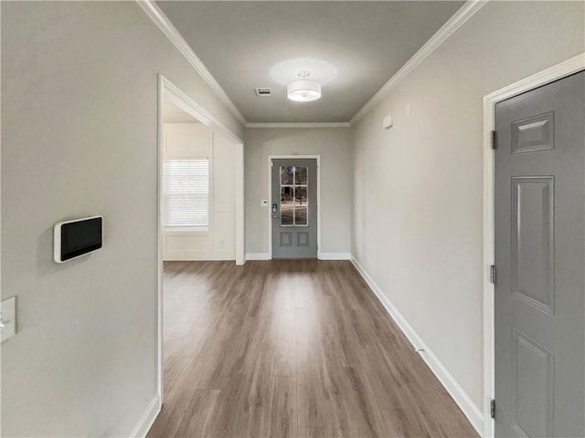 interior space with baseboards, wood finished floors, visible vents, and crown molding