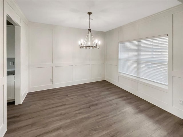 unfurnished dining area with a chandelier, a decorative wall, and dark wood-style floors