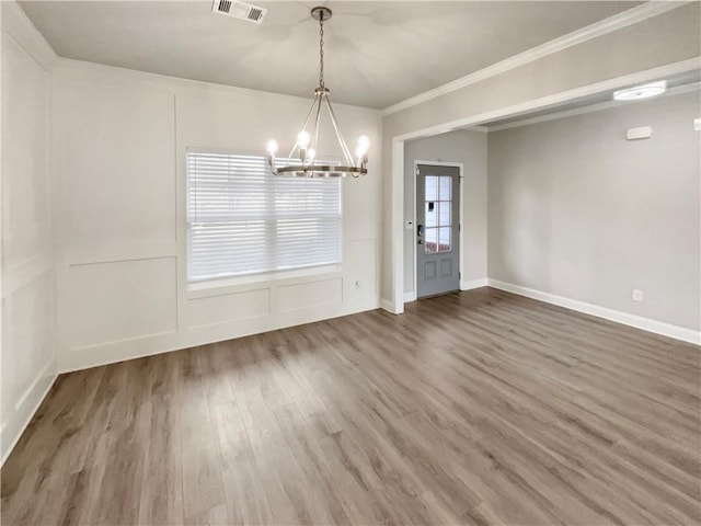 unfurnished dining area featuring a notable chandelier, wood finished floors, visible vents, baseboards, and ornamental molding