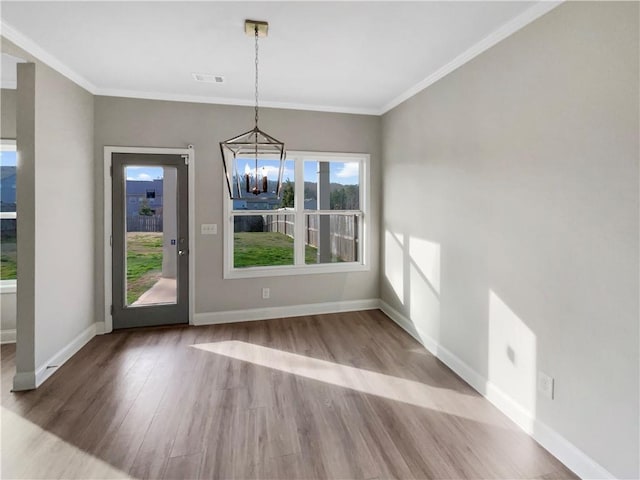 unfurnished dining area with a chandelier, wood finished floors, visible vents, baseboards, and ornamental molding