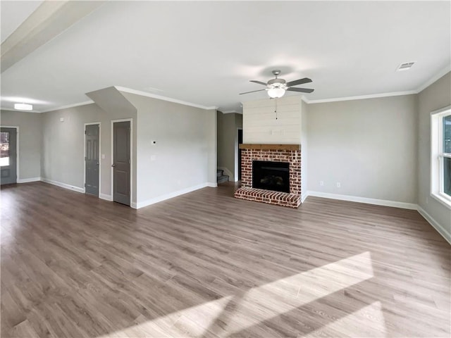 unfurnished living room with baseboards, visible vents, ornamental molding, wood finished floors, and a fireplace