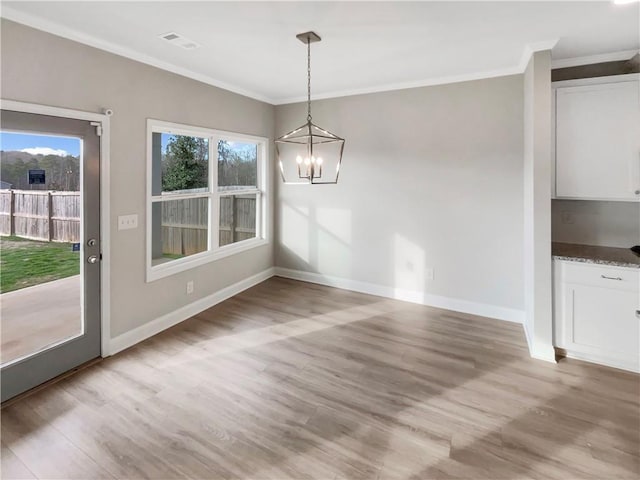 unfurnished dining area featuring light wood finished floors, baseboards, visible vents, and ornamental molding