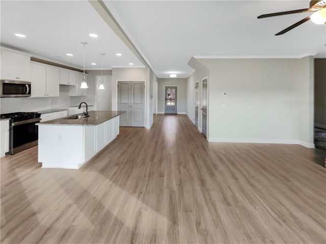 kitchen with appliances with stainless steel finishes, open floor plan, white cabinets, and a sink