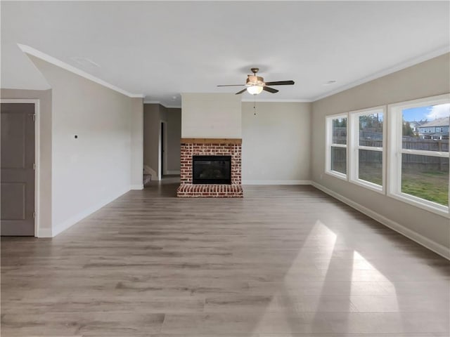 unfurnished living room featuring light wood-type flooring, ornamental molding, a brick fireplace, and baseboards