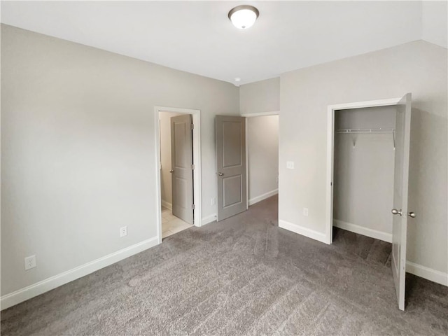 unfurnished bedroom with carpet floors, baseboards, vaulted ceiling, and a closet