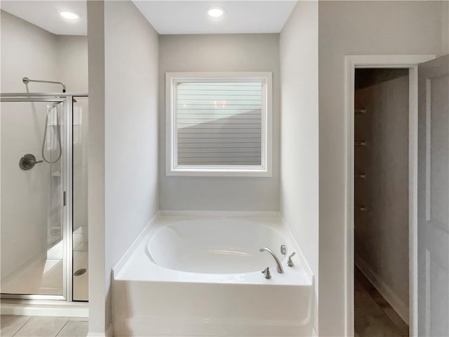 full bath with a stall shower and a garden tub