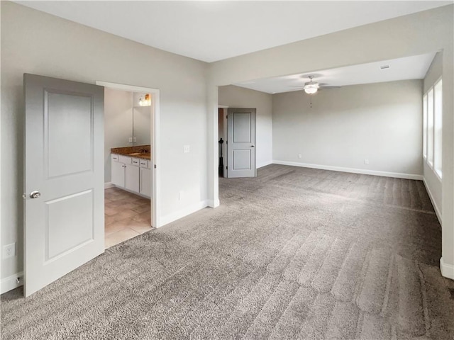 unfurnished bedroom with light carpet, baseboards, and connected bathroom