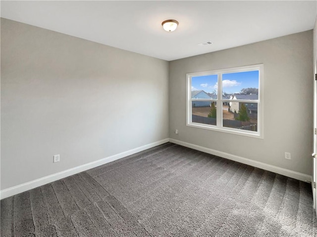 unfurnished room with visible vents, baseboards, and dark colored carpet