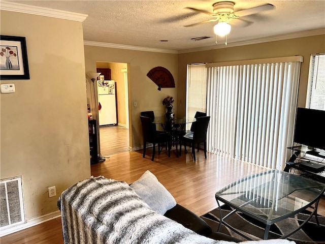 living room with hardwood / wood-style floors, crown molding, a textured ceiling, and ceiling fan