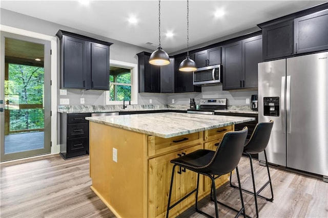 1441 Whitestone Rd, Talking Rock, GA 30175 - kitchen with stainless steel appliances, a kitchen island, light stone countertops, a breakfast bar area, and light wood-type flooring