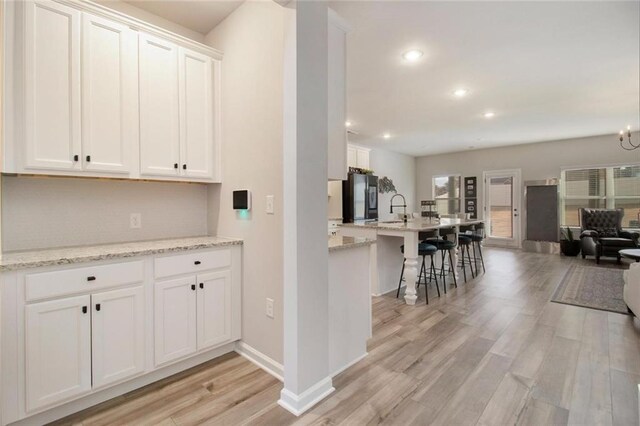 kitchen featuring light wood-style floors, freestanding refrigerator, open floor plan, and a sink