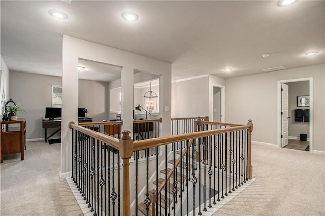 corridor featuring carpet floors, baseboards, and an upstairs landing