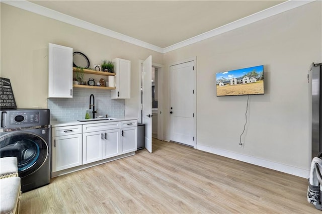 2634 Greenes Ln, Powder Springs, GA 30127 - washroom featuring light wood finished floors, cabinet space, ornamental molding, a sink, and washer / dryer