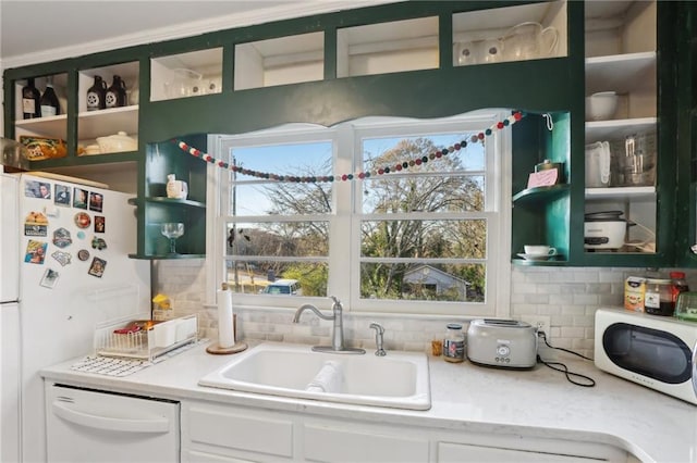 kitchen with backsplash, white cabinetry, white appliances, and sink