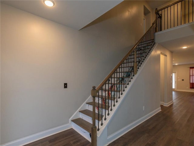 staircase with a towering ceiling and hardwood / wood-style floors