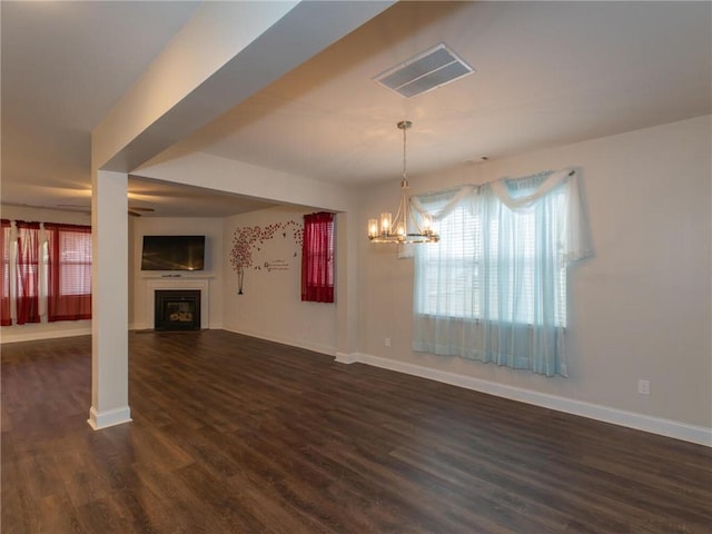 unfurnished living room featuring an inviting chandelier and dark wood-type flooring