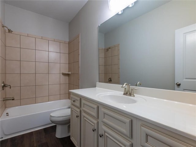 full bathroom with vanity, hardwood / wood-style floors, tiled shower / bath, and toilet