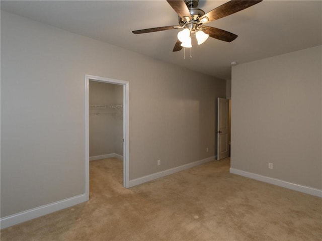 unfurnished bedroom with a walk in closet, light colored carpet, ceiling fan, and a closet