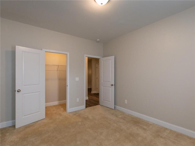 unfurnished bedroom with a walk in closet, light carpet, and a closet