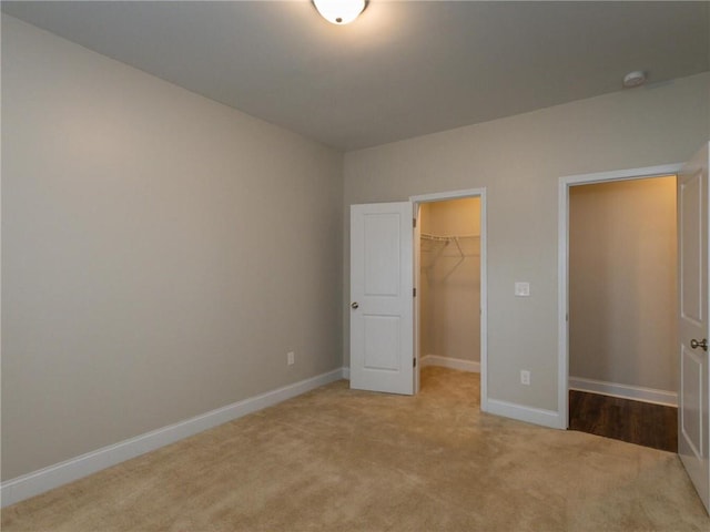 unfurnished bedroom with a closet, a spacious closet, and light carpet