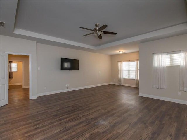 empty room featuring dark wood-type flooring, ceiling fan, and a tray ceiling