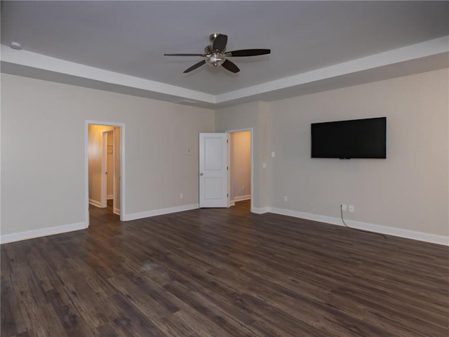 interior space with a tray ceiling, dark hardwood / wood-style floors, and ceiling fan